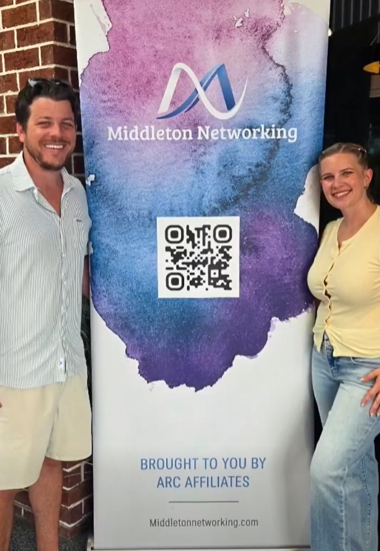 Ty and Shelbi Arcand, founders of Middleton Networking, beside the Middleton Networking banner at a Networking Night